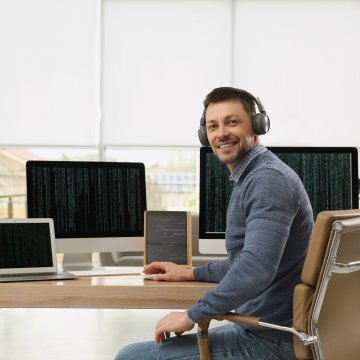 Guy smiling at his computer with headphones on 